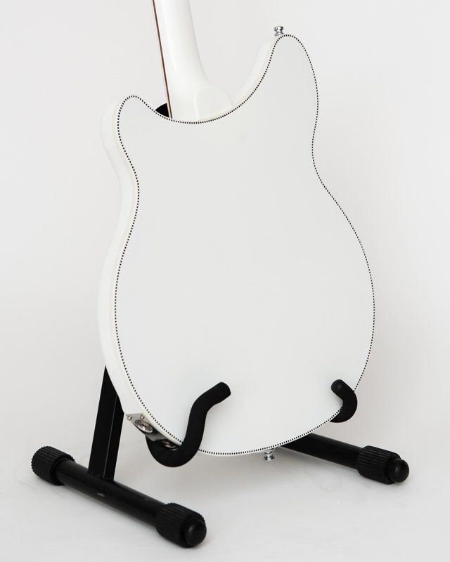 A white guitar is sitting on a black stand