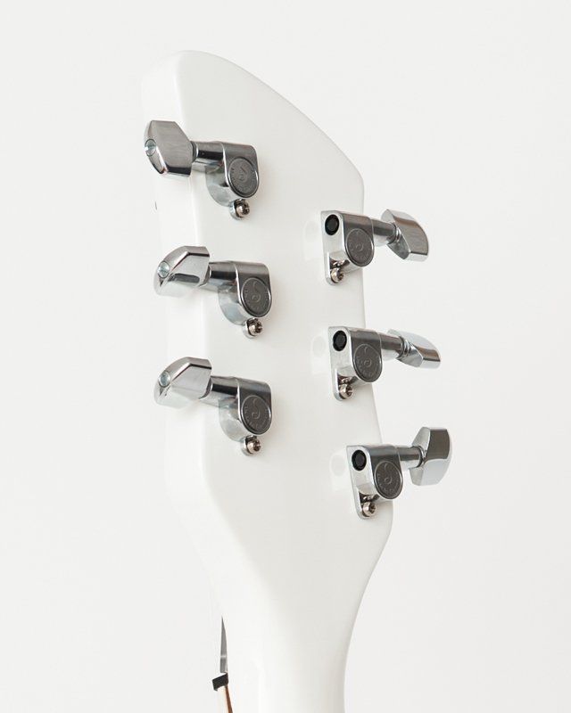 A close up of a white guitar headstock with chrome tuners
