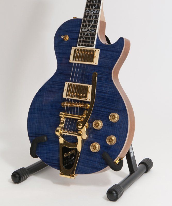 A blue electric guitar is sitting on a stand