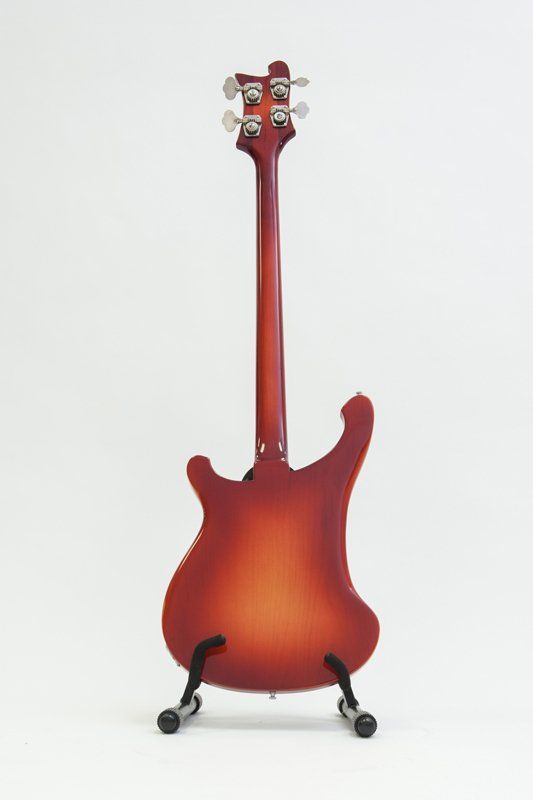 A red electric guitar is sitting on a stand on a white background.