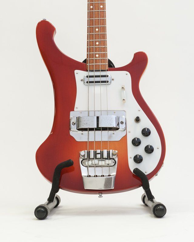 A red bass guitar is sitting on a stand