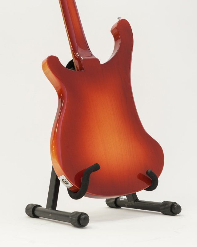 A red electric guitar is sitting on a stand