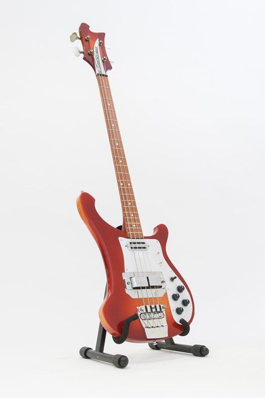 A red electric guitar is sitting on a stand on a white background.