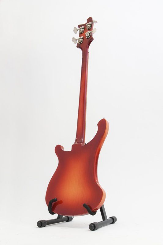 A red electric guitar is sitting on a stand on a white background.