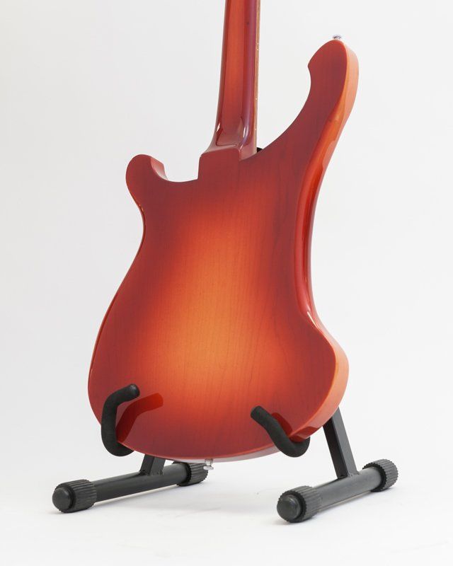 A red electric guitar is sitting on a stand