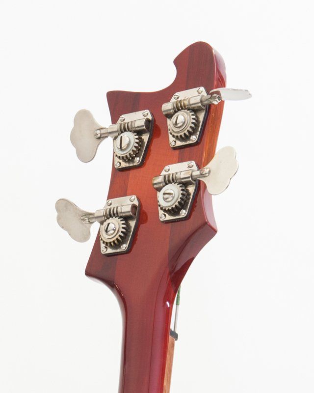 A close up of the headstock of a bass guitar on a white background.