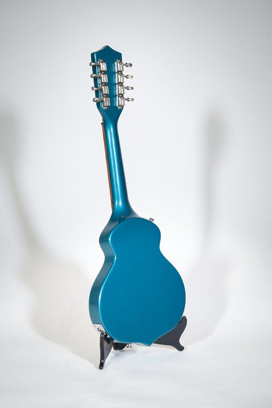 A blue guitar is sitting on a stand on a white surface.
