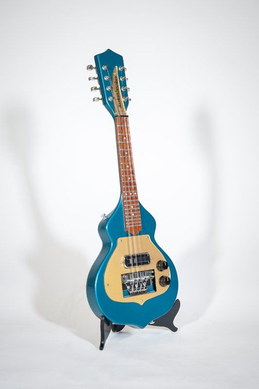 A blue guitar is sitting on a stand on a white background.