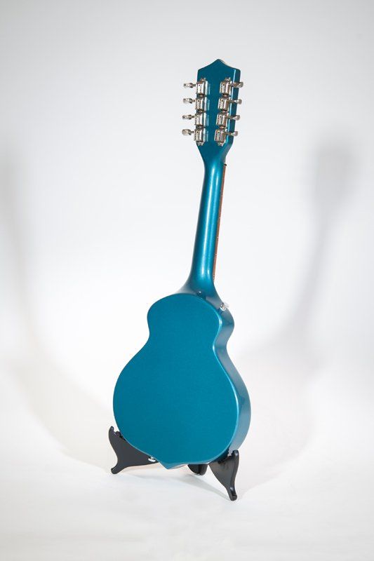 A blue guitar is sitting on a stand on a white background.