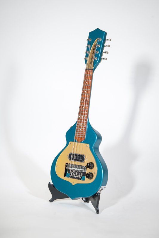A blue guitar is sitting on a stand on a white background