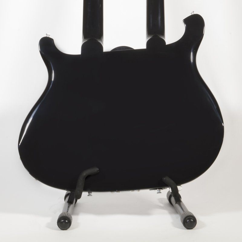 The back of a black guitar is shown on a stand