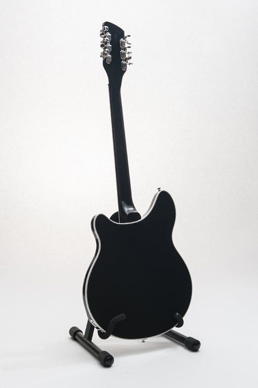 The back of a black electric guitar on a stand