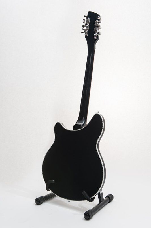 A black guitar is sitting on a stand on a white background