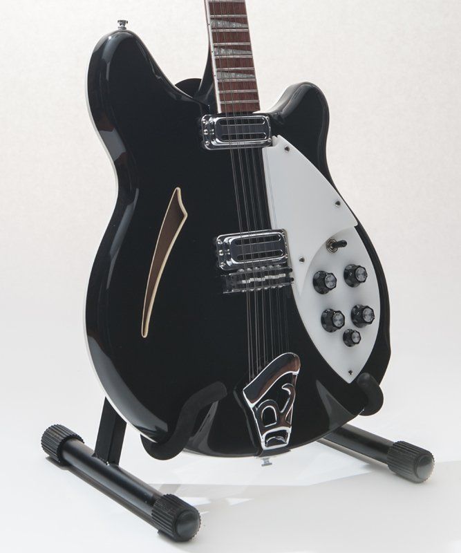 A black and white guitar is sitting on a stand