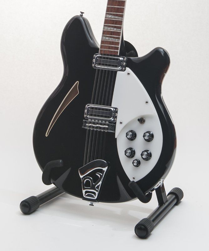 A black and white guitar is sitting on a stand