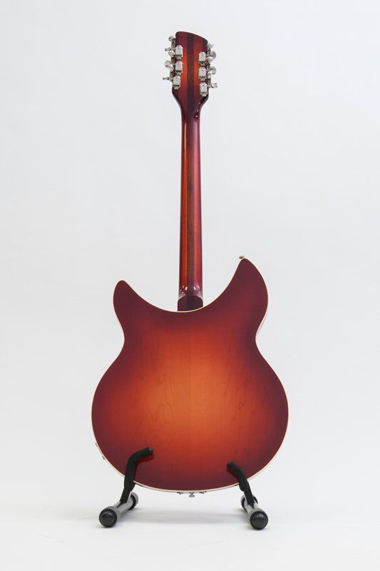 A red guitar is sitting on a stand on a white background.