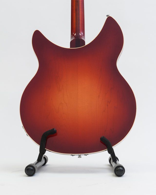 A red guitar is sitting on a stand on a white background