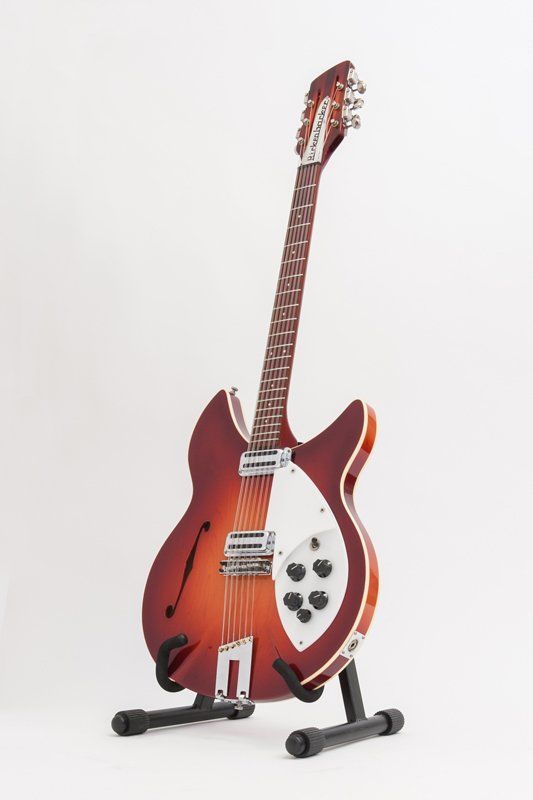 A red guitar is sitting on a stand on a white background.