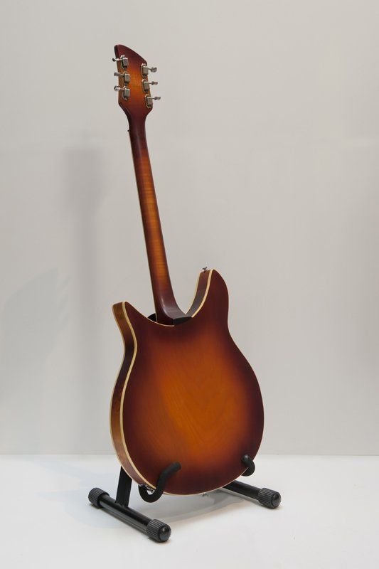 A guitar is sitting on a stand on a white surface