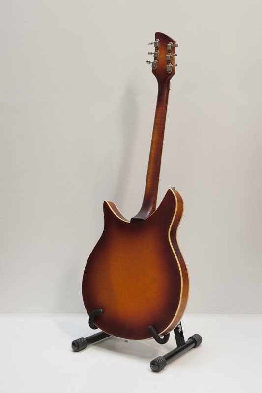 A guitar is sitting on a stand on a table.