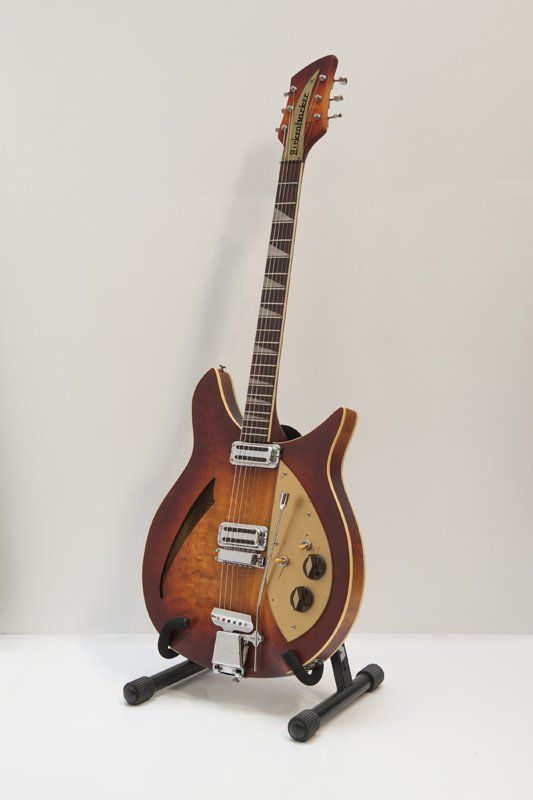 A guitar is sitting on a stand on a table.
