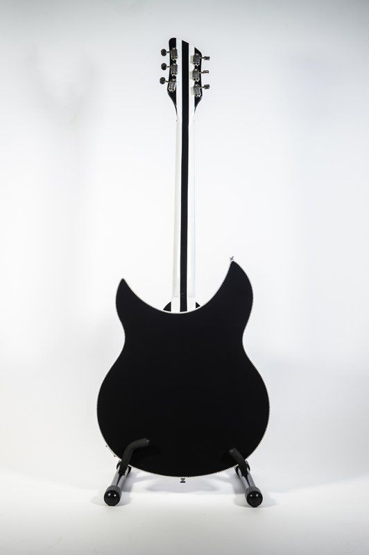 A black guitar is sitting on a stand on a white background.