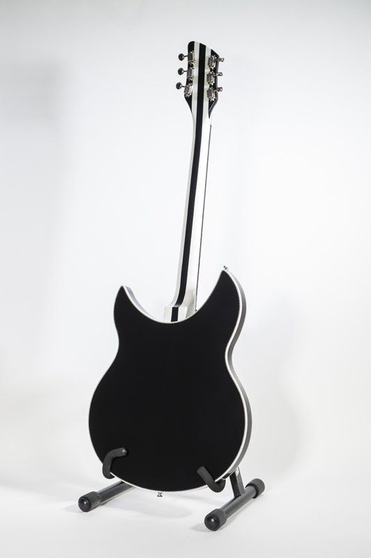 A black and white electric guitar is sitting on a stand.