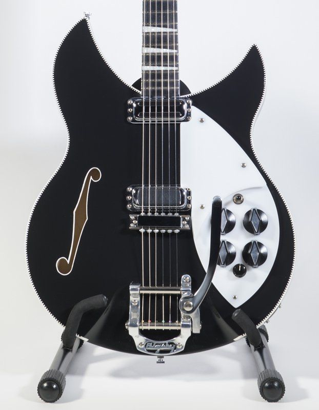 A black and white guitar is sitting on a stand