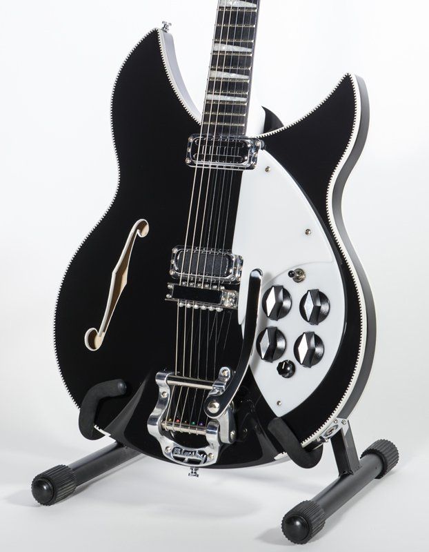 A black and white guitar is sitting on a stand