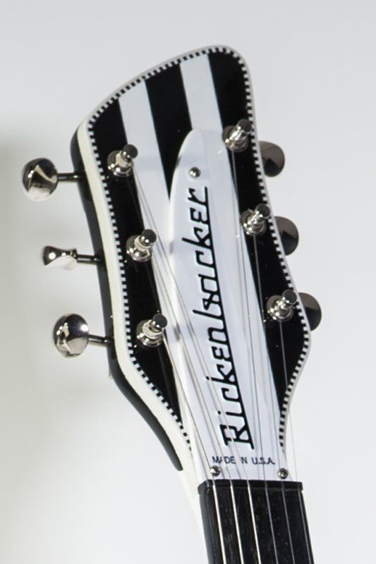 The headstock of a black and white rickenbacker guitar