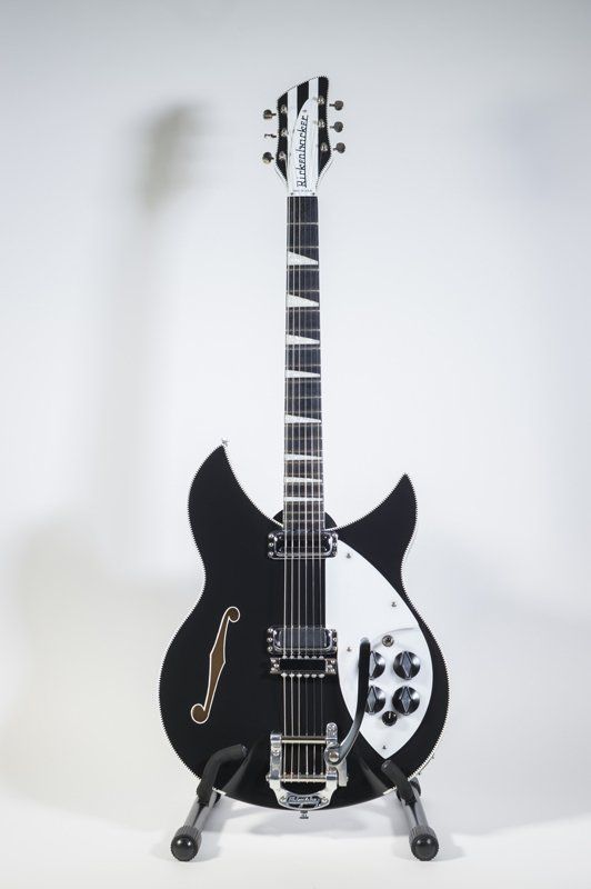 A black and white electric guitar is sitting on a stand.