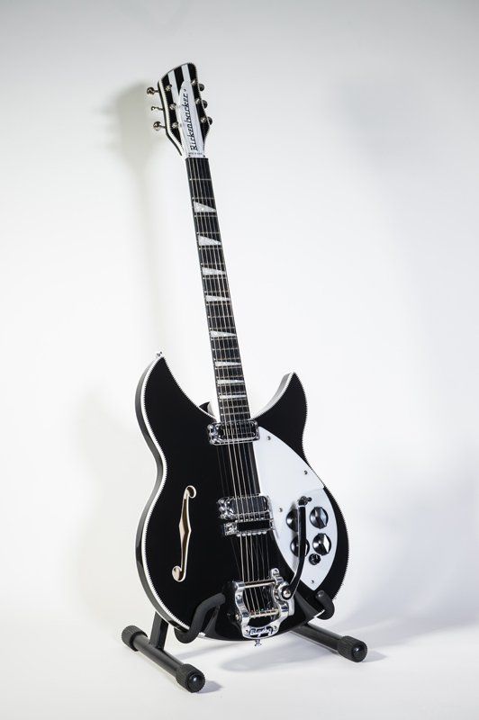 A black and white electric guitar is sitting on a stand.