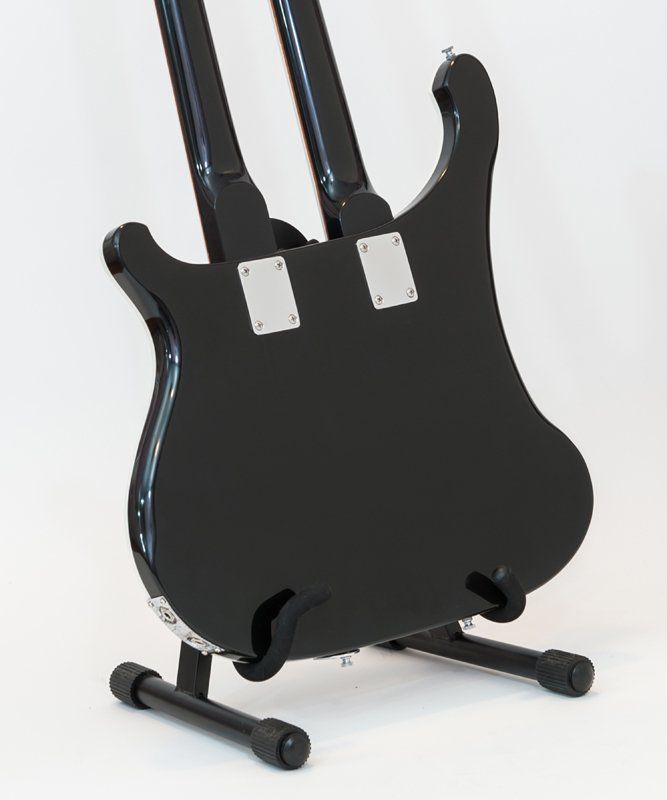 A black double neck guitar is sitting on a stand