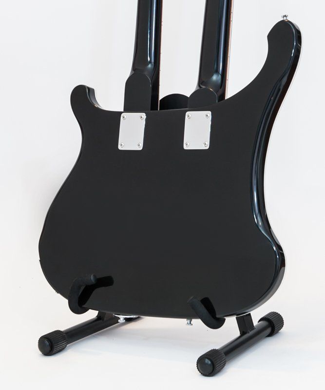 A black double neck guitar is sitting on a stand