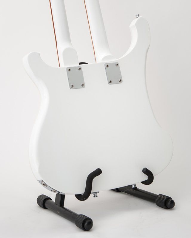 A white guitar is sitting on a black stand