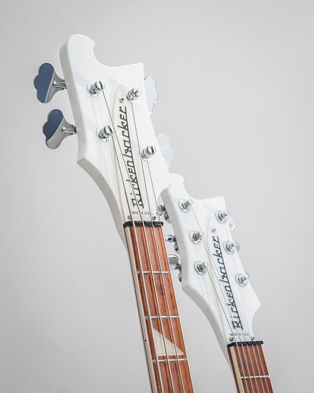 Two white rickenbacker guitars are sitting next to each other