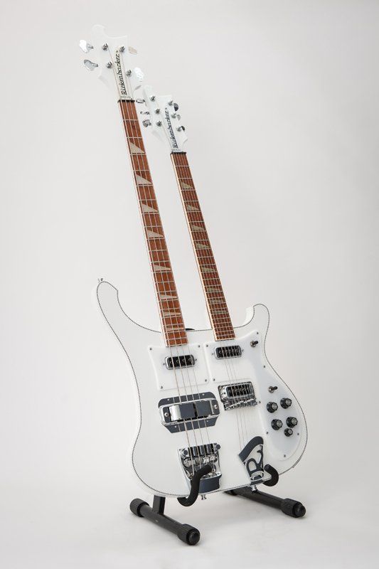 A white double neck guitar is sitting on a stand