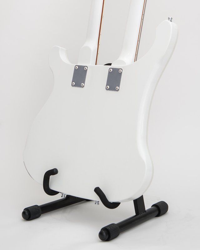 A white guitar is sitting on a black stand
