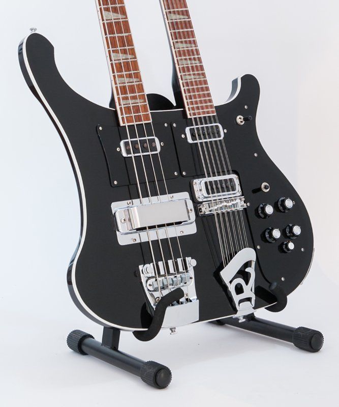 A black double neck guitar is sitting on a stand