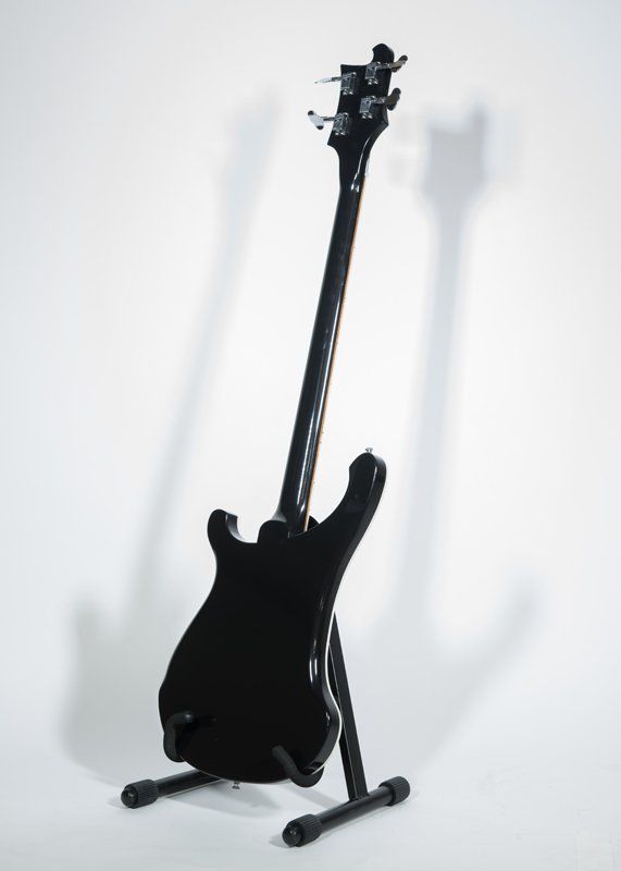 A black electric guitar is sitting on a stand