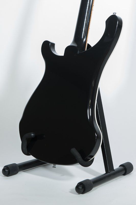 The back of a black electric guitar on a stand