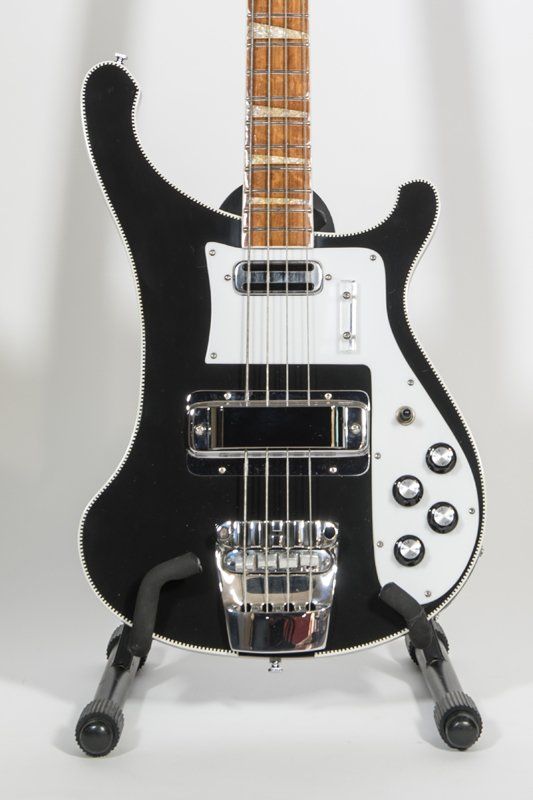 A black and white bass guitar is sitting on a stand