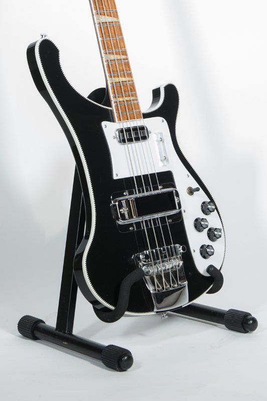 A black and white electric guitar is sitting on a stand.