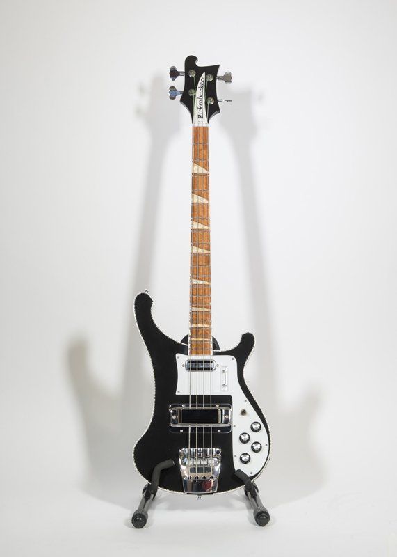 A black and white bass guitar is sitting on a stand.
