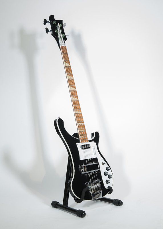 A black and white electric guitar is sitting on a stand.