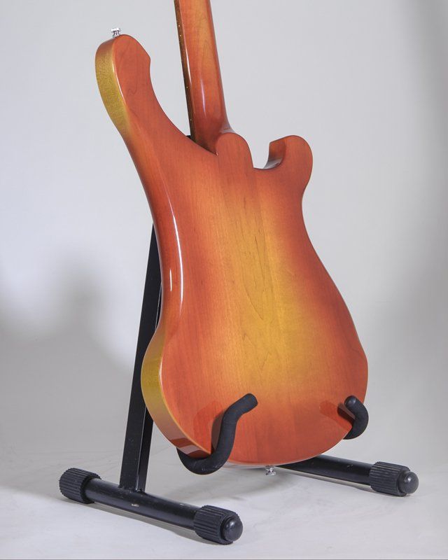 A red and yellow guitar is sitting on a stand
