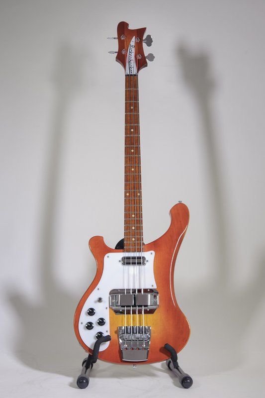 A rickenbacker bass guitar is sitting on a stand