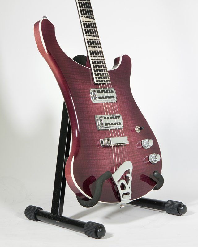 A purple electric guitar is sitting on a black stand