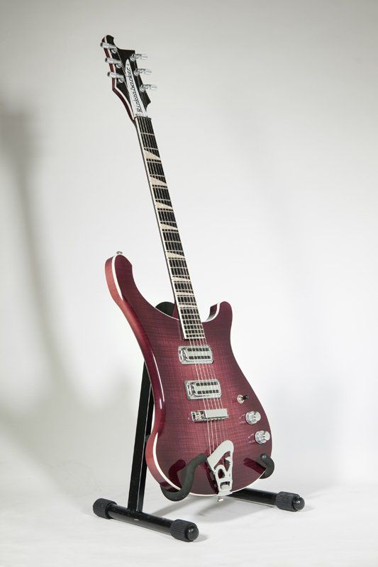 A purple electric guitar is sitting on a stand