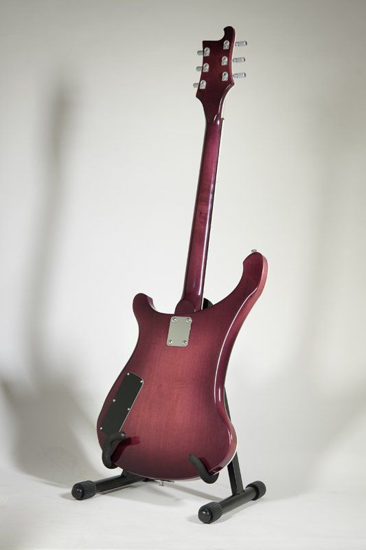 A red electric guitar is sitting on a stand on a white background.